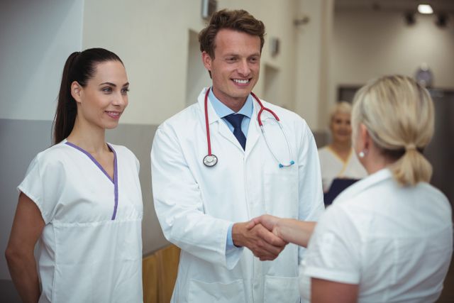 Doctor shaking hand with nurse in corridor - Download Free Stock Photos Pikwizard.com