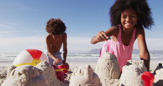 African american brother and sister playing with sand on the beach. family outdoor leisure time by the sea.