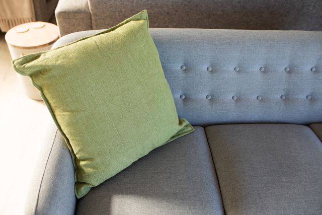 Close of green fabric cushion on grey fabric sofa in living room modern interiors. Domestic life interiors modern decor.
