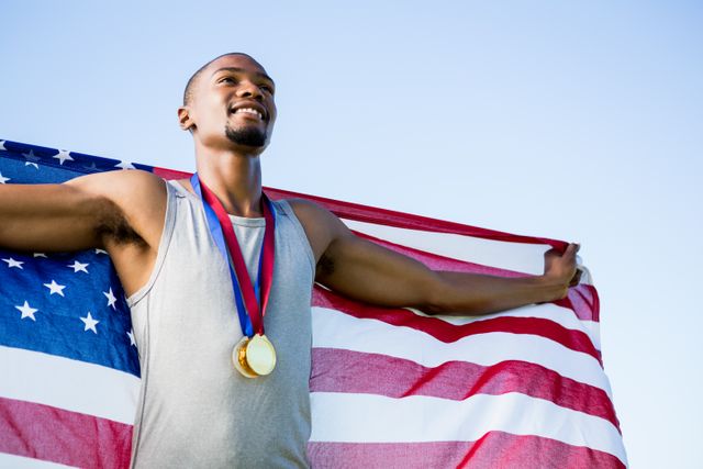 Athlete posing with american flag and gold medals around his neck in stadium