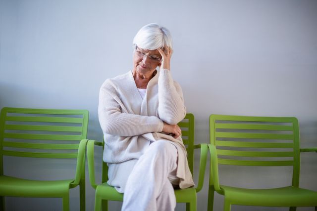 Tensed senior woman sitting on chair in waiting area - Download Free Stock Photos Pikwizard.com