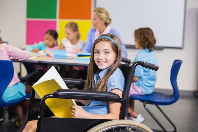 Disabled school girl on wheelchair holding a book in classroom - Download Free Stock Photos Pikwizard.com