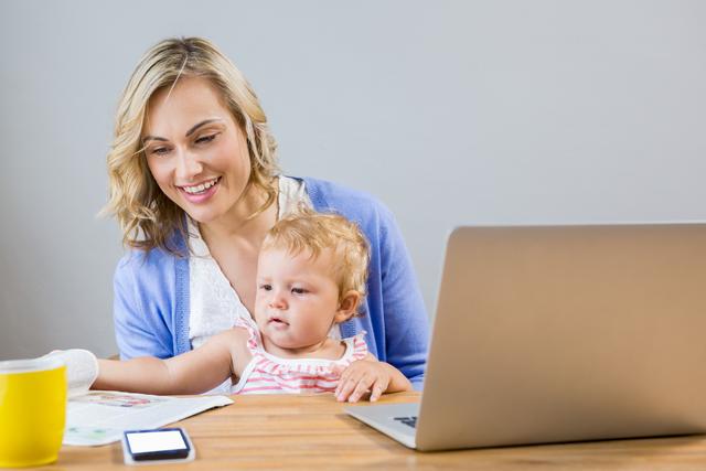 Mother holding baby girl while using laptop - Download Free Stock Photos Pikwizard.com