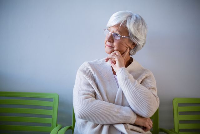 Thoughtful senior woman sitting on chair in hospital