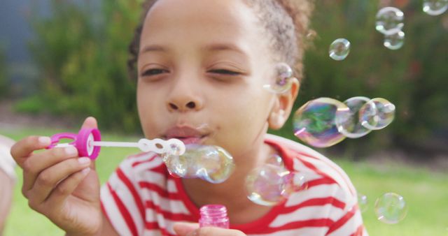 Happy african american girl having fun blowing bubbles in garden. Childhood, fun, summer, health and relaxation.