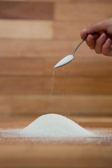 Woman hand pouring sugar from spoon - Download Free Stock Photos Pikwizard.com