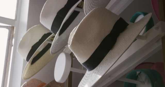 Close up of straw hats, trilbys and various other hats hanging on display in the showroom at a hat factory, in slow motion