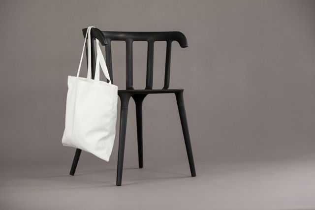 White shopping bag hanging on black chair - Download Free Stock Photos Pikwizard.com