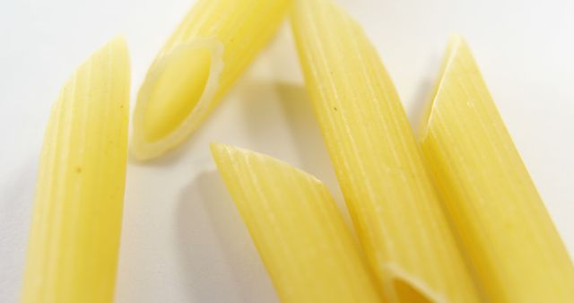 Close-up of uncooked penne pasta on a white background, with copy space  from Pikwizard