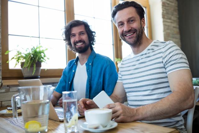 Two smiling men sitting at table in coffee shop - Download Free Stock Photos Pikwizard.com