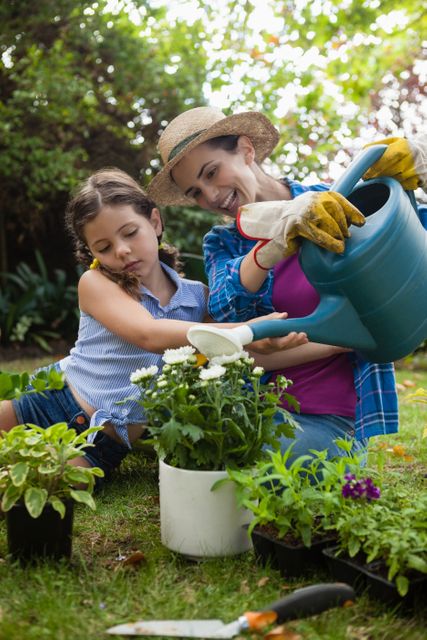 Happy mother with daughter watering potted plants in backyard - Download Free Stock Photos Pikwizard.com