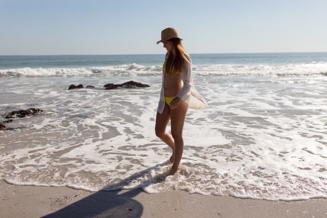 Beautiful woman in bikini and hat walking on beach in the sunshine - Download Free Stock Photos Pikwizard.com