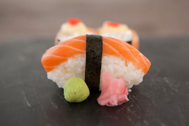 Nigiri and uramaki sushi served on black stone slate on wooden table - Download Free Stock Photos Pikwizard.com