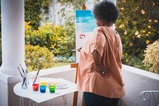 African american senior woman painting on canvas on terrace in sunny garden - Download Free Stock Photos Pikwizard.com