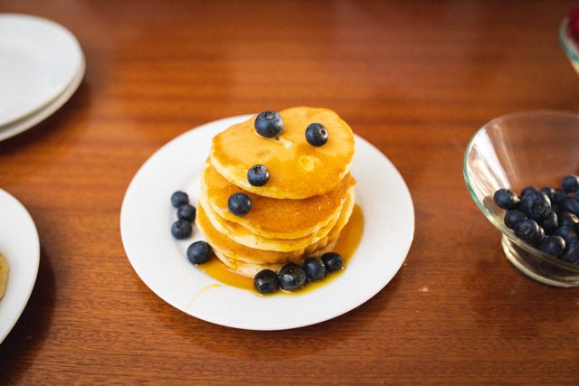 Close-up of stacked pancakes with syrup and blueberries served in plate on table - Download Free Stock Photos Pikwizard.com