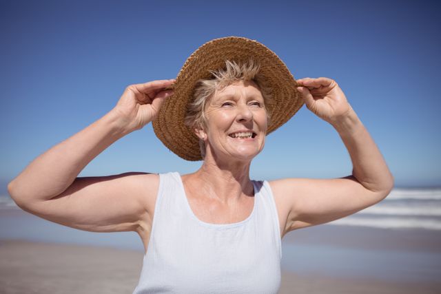 Smiling senior woman wearing sun hat at beach - Download Free Stock Photos Pikwizard.com