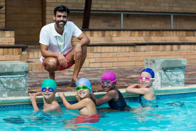 Happy male trainer with little swimmers at poolside - Download Free Stock Photos Pikwizard.com