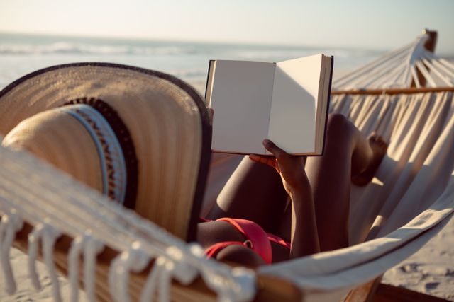 Woman reading a book while relaxing in hammock on the beach - Download Free Stock Photos Pikwizard.com