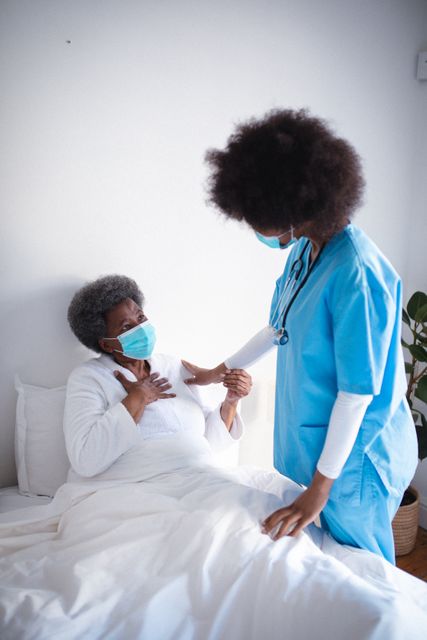 African american female doctor wearing face mask treating senior woman at home - Download Free Stock Photos Pikwizard.com