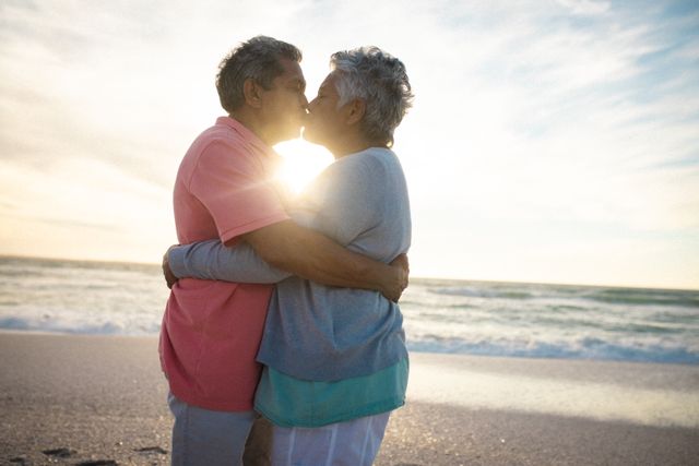 Side view of affectionate senior couple embracing while kissing each other at beach during sunset - Download Free Stock Photos Pikwizard.com