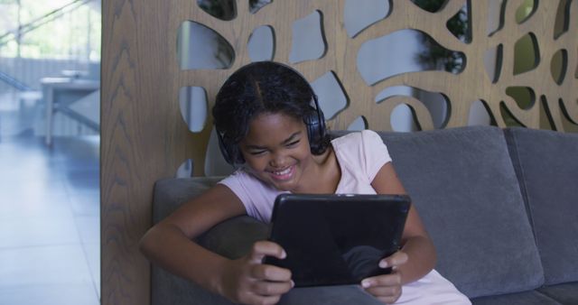 African american girl smiling while using digital tablet sitting on the couch at hospital. medical healthcare during coronavirus covid 19 pandemic concept