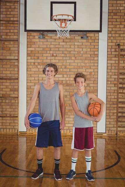 Smiling school boys holding basketball in the court - Download Free Stock Photos Pikwizard.com