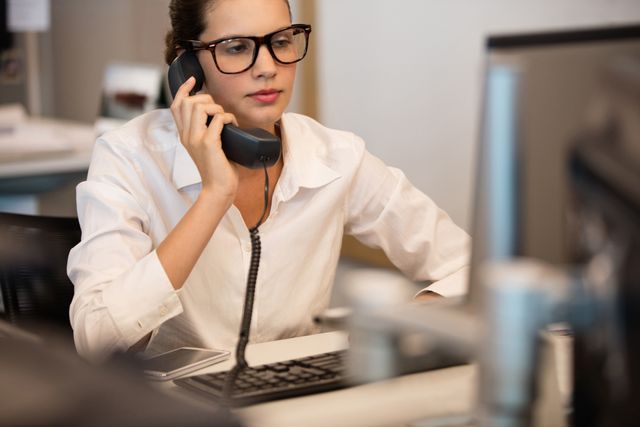 Businesswoman using telephone while sitting at office - Download Free Stock Photos Pikwizard.com