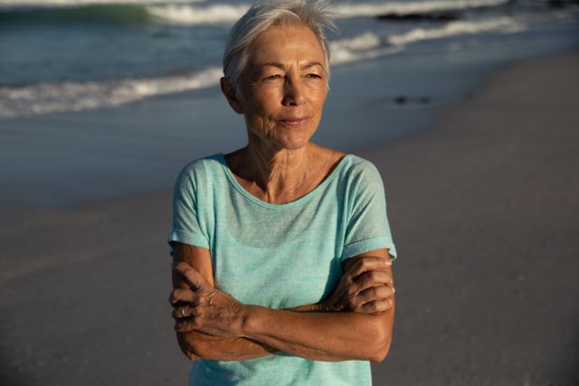 Senior woman standing with her arms crossed on the beach - Download Free Stock Photos Pikwizard.com