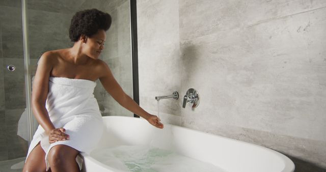 Happy african american woman preparing bath in bathroom. domestic lifestyle, spending free time at home.