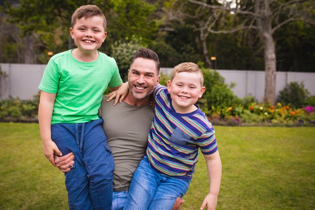 Portrait of caucasian father and two sons smiling together in the garden - Download Free Stock Photos Pikwizard.com