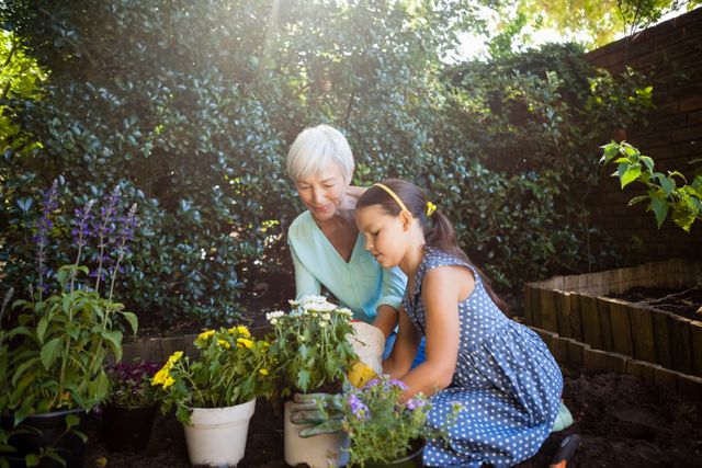 Grandmother looking at girl planting flower pots - Download Free Stock Photos Pikwizard.com