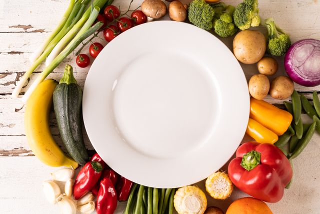 Directly above view of empty white plate with copy space amidst various fresh vegetables on table - Download Free Stock Photos Pikwizard.com