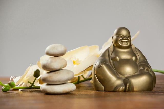 Laughing buddha figurine with pebbles stone and flower - Download Free Stock Photos Pikwizard.com