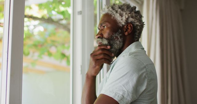 Portrait of african american senior man with beard looking out of window and thinking - Download Free Stock Photos Pikwizard.com