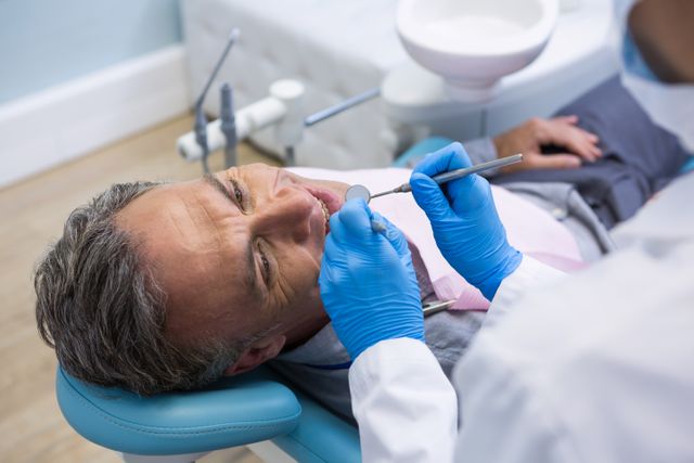 High angle view of dentist examining senior man mouth at medical clinic