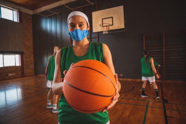 Portrait of caucasian female basketball player wearing face mask holding ball in court - Download Free Stock Photos Pikwizard.com