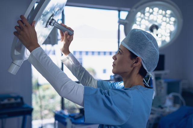 Female surgeon adjusting surgical light in operating room at hospital
