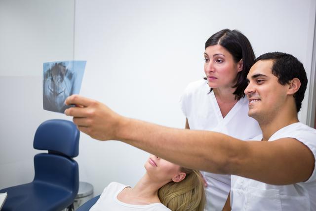 Dentists discussing x-ray in front of patient - Download Free Stock Photos Pikwizard.com