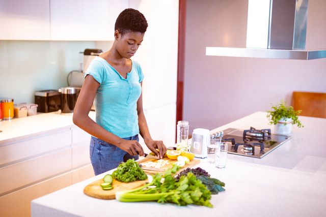 African american woman standing in kitchen, chopping vegetables for smoothie - Download Free Stock Photos Pikwizard.com