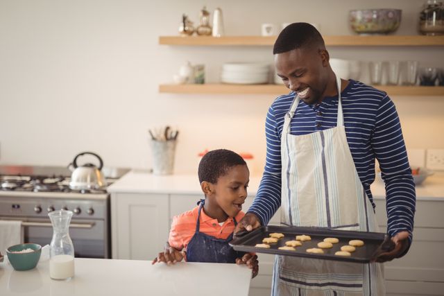 Father holding tray while son looking at cookies - Download Free Stock Photos Pikwizard.com