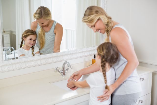 Happy mother and daughter washing hands in bathroom sink - Download Free Stock Photos Pikwizard.com