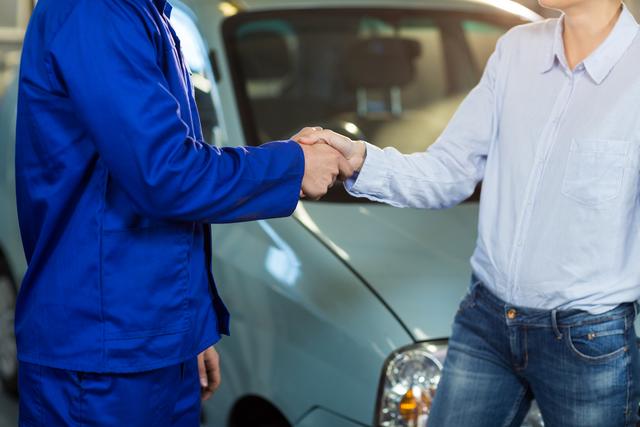 Mid-section of customer shaking hands with mechanic - Download Free Stock Photos Pikwizard.com