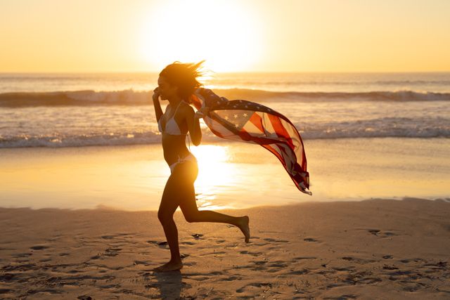 Young woman with an American flag running on the beach