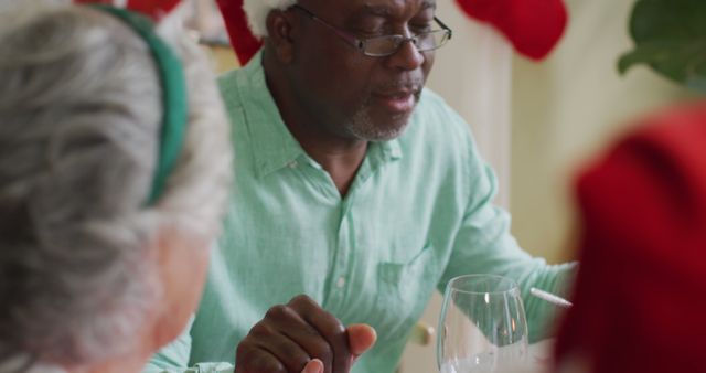 Happy african american senior man praying with friends, celebrating meal at christmas time - Download Free Stock Photos Pikwizard.com