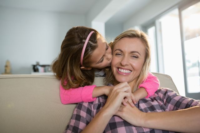 Girl kissing her mother in the living room at home