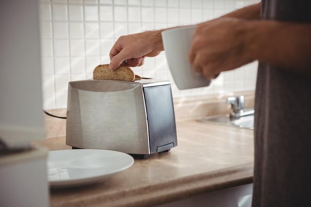 Man toasting bread for breakfast and drinking coffee - Download Free Stock Photos Pikwizard.com