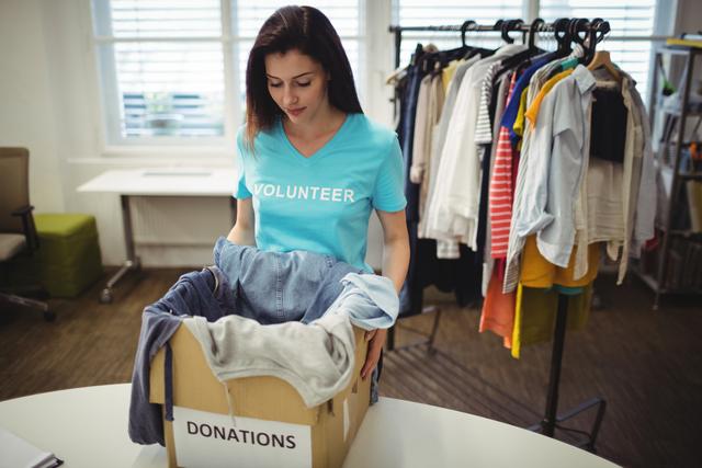Female volunteer holding clothes in donation box - Download Free Stock Photos Pikwizard.com