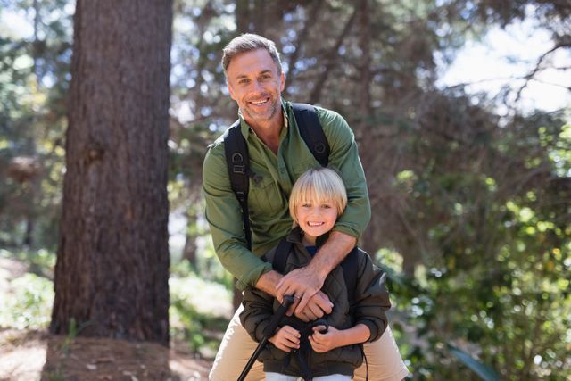 Happy father and son standing against trees in forest - Download Free Stock Photos Pikwizard.com