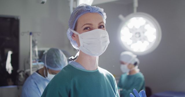 Image portrait of caucasian female surgeon in face mask smiling in operating theatre, copy space. Hospital, medical and healthcare services.