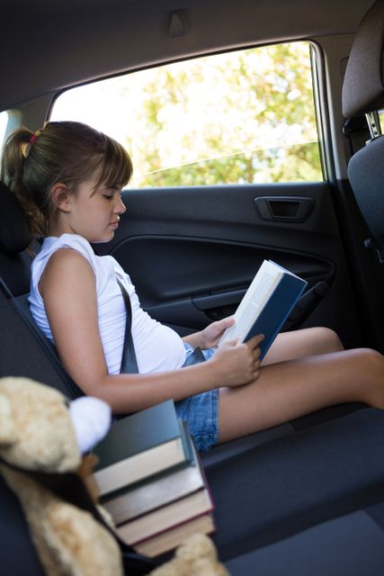 Teenage girl reading book in the back seat of car - Download Free Stock Photos Pikwizard.com